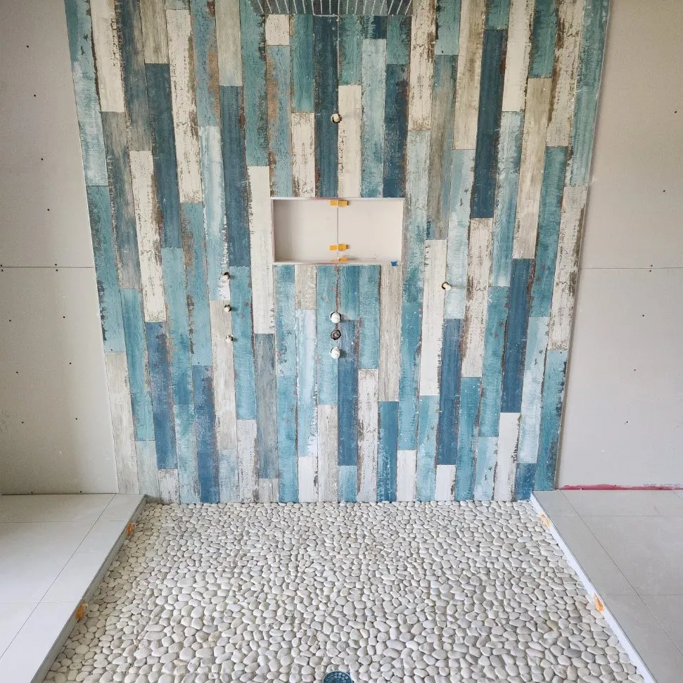 Blue glass tile shower with pebble shower pan