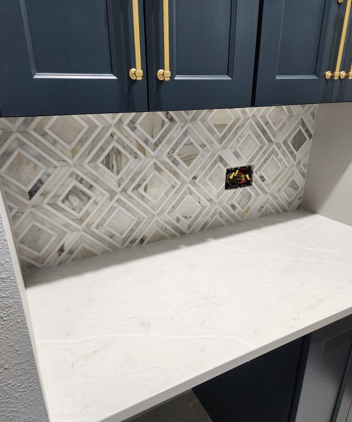 Geometric mosaic tile backsplash with navy cabinets