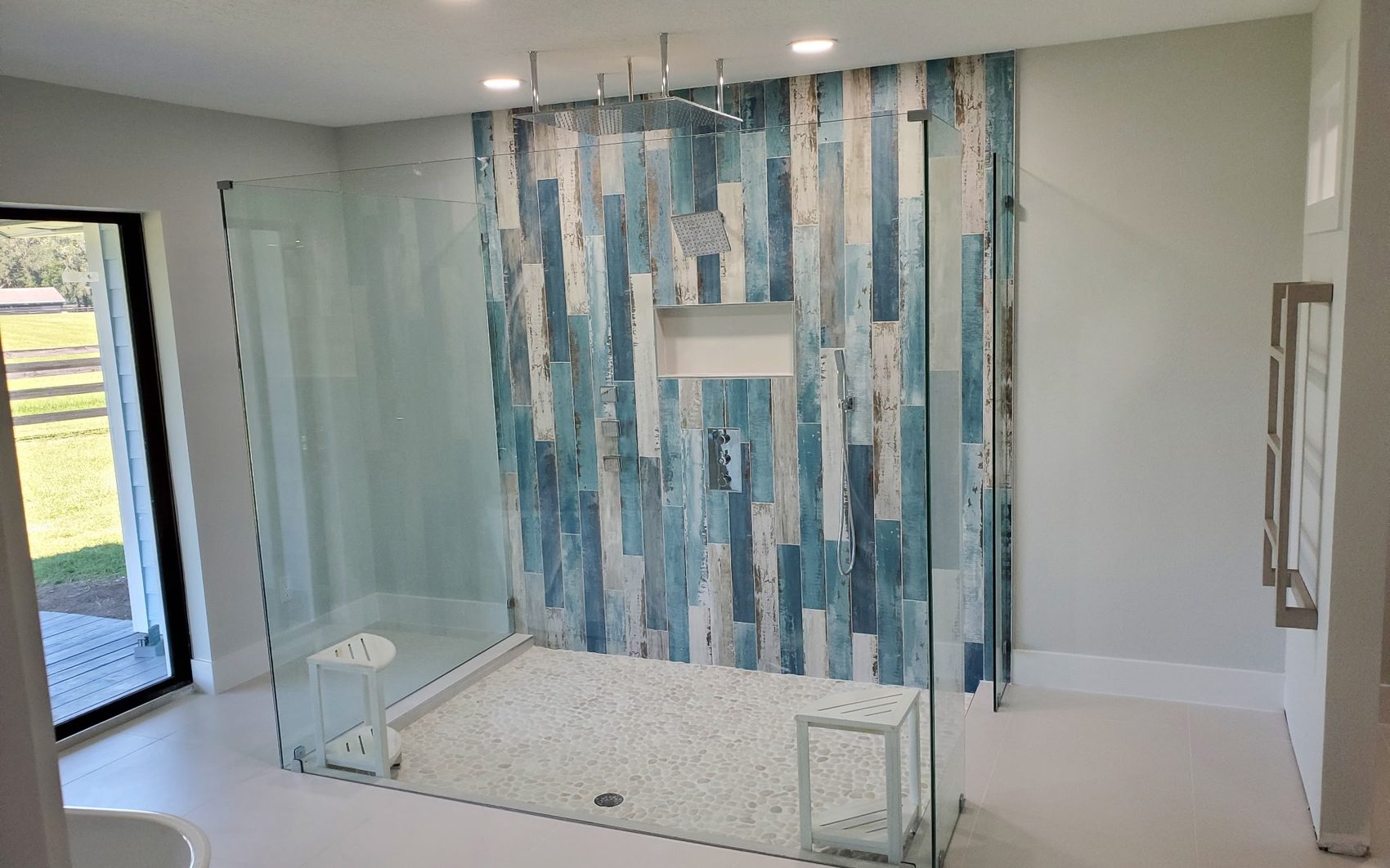 Walk-in glass shower with blue glass tile feature wall