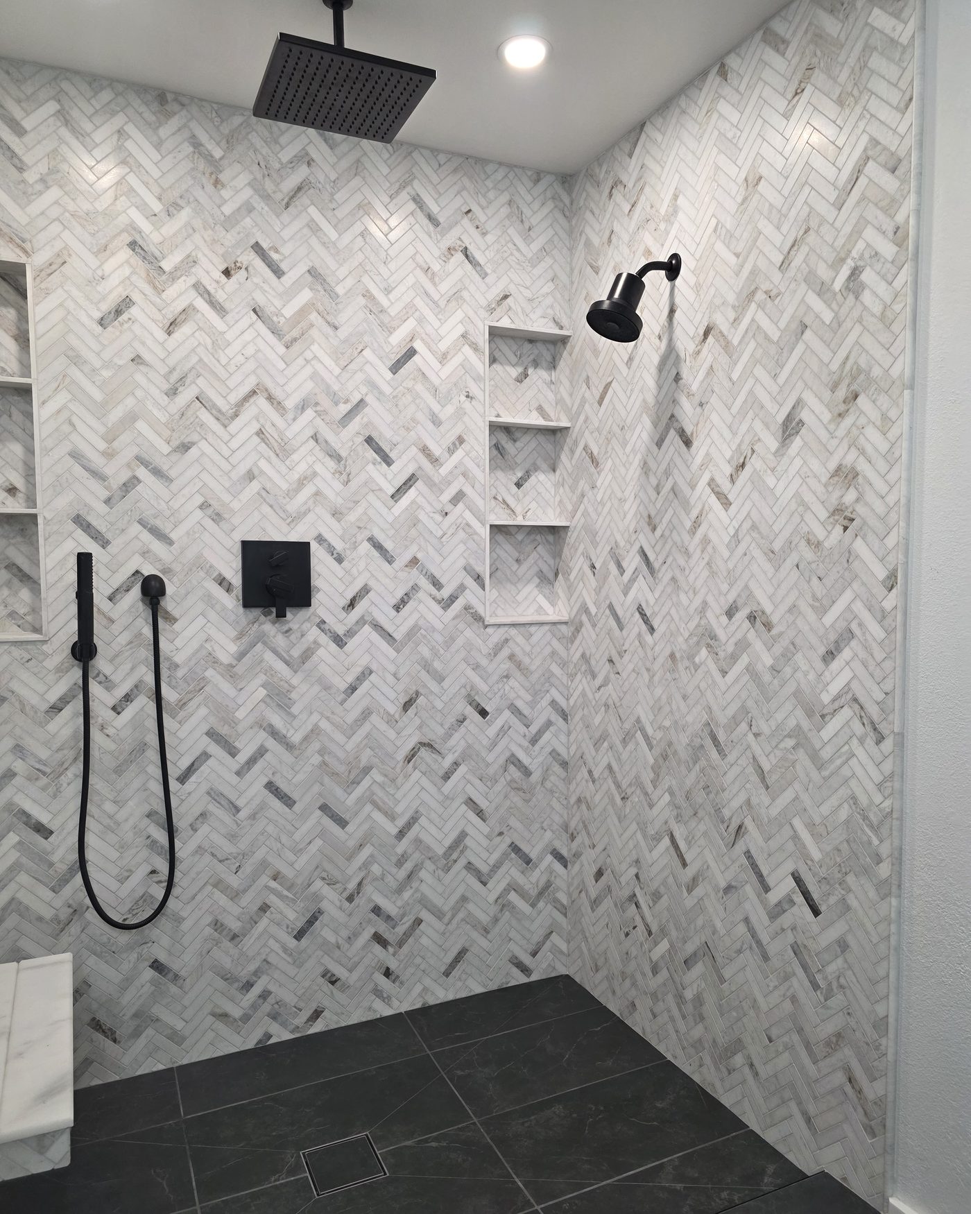 Herringbone marble tile shower with black fixtures, built in Central Florida