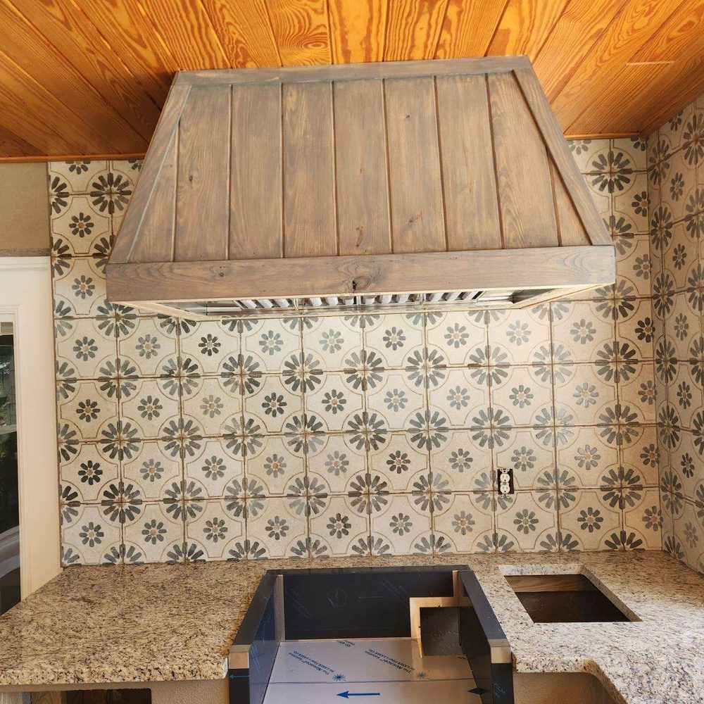 Patterned cement-look kitchen backsplash under a wood hood